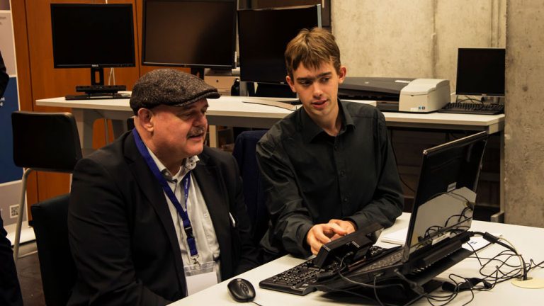 Foto: Zwei PErsonen sitzen vor einem PC mit Eyetracker beim WUD 2016