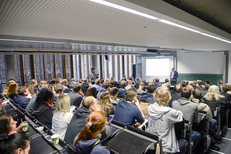 Foto: Voller Hörsaal beim WUD 2017 aus der letzten Reihe nach vorne